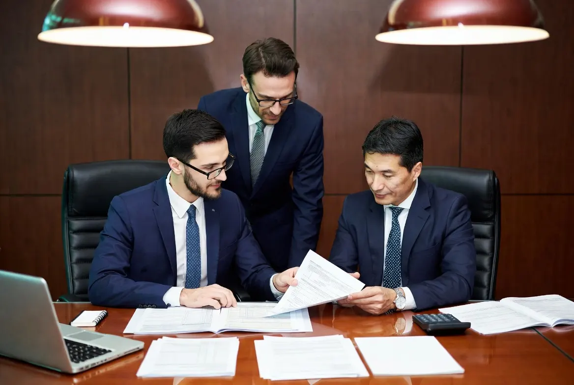 Two business partners seated across a desk from a tax advisor reviewing a printed Form 1065 draft and Schedule K-1 documents in a professional Mokena office